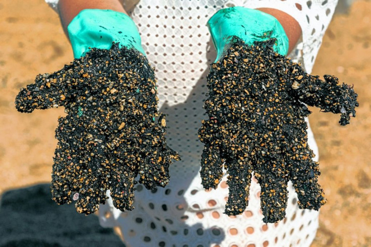 A volunteer shows his crude-encrusted gloves at Praia de Busca Vida beach in Bahia state during a cleanup operation on November 3