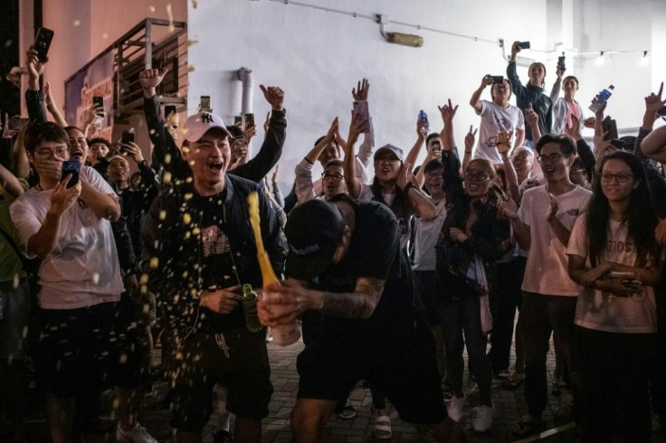 A pro-democracy supporter (center) opens a bottle of champagne outside a polling station to celebrate after pro-Beijing candidate Junius Ho lost a seat in the district council elections in the Tuen Mun district of Hong Kong on November 25, 2019