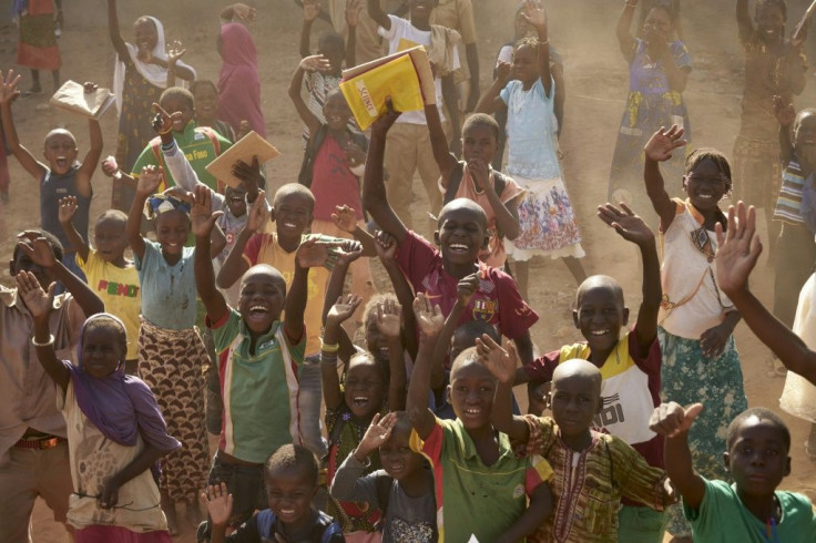 Burkinabe children, waving at French troops passing by in armoured personnel carriers