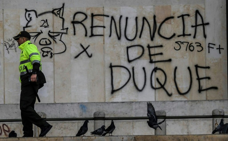 A policeman walks by graffiti calling on Colombian President Ivan Duque to resign, in Bogota on November 24