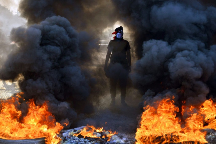 An Iraqi protester stands before burning tires at a roadblock in the central holy shrine city of Najaf