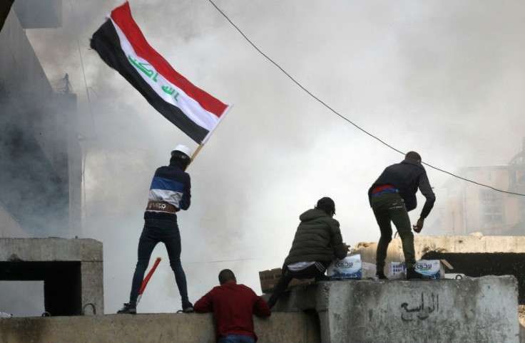Protesters wave the Iraqi flag amid clashes in Baghdad's Al-Rasheed street on November 26, 2019