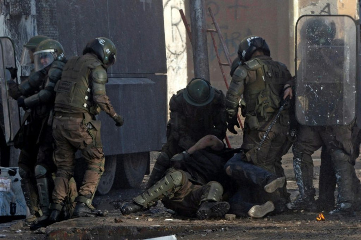 Chilean riot police, accused of using excessing force, arrest a demonstrator during an anti-government protest in Santiago