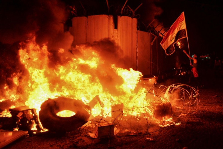 The Iraqi flag is brandished by demonstrators after they set fire to Iran's consulate in Najaf