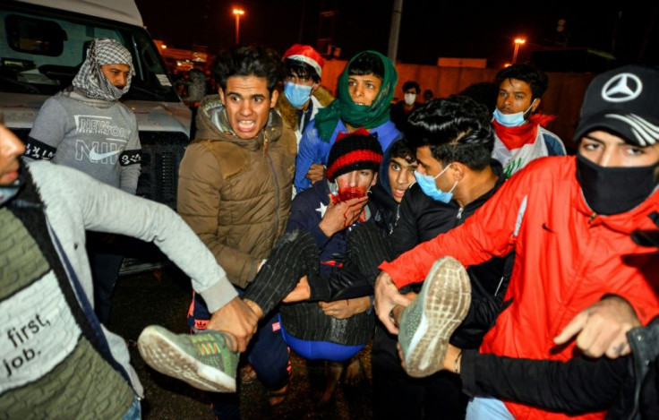 Iraqis carry an injured anti-government protester during clashes with security forces in the central holy shrine city of Najaf on November 28, 2019