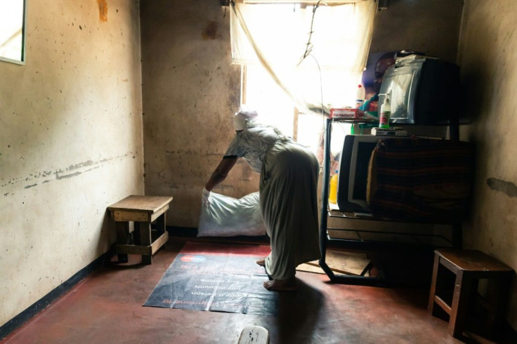 Where a child is born: Esther Gwena, 69, who acts as a midwife but has no training, lays down sheets in her rundown apartment -- a makeshift maternity unit