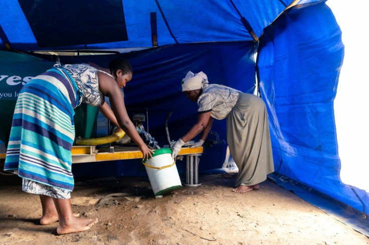 Gwena collects water in a bucket as she prepares for a long day