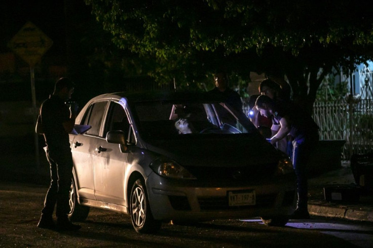 Experts work at a crime scene where a man was shot dead in Culiacan -- the victim is inside the car