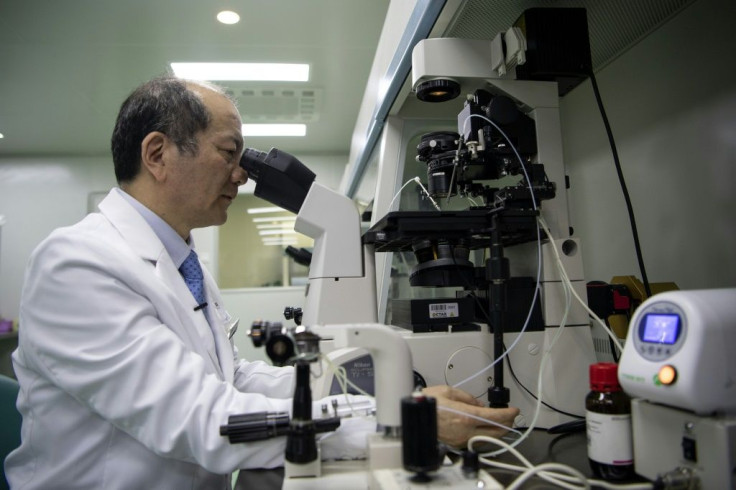 Liu Jiaen, director of a fertility hospital, looking at a sperm sample through a microscope at the hospital in Beijing