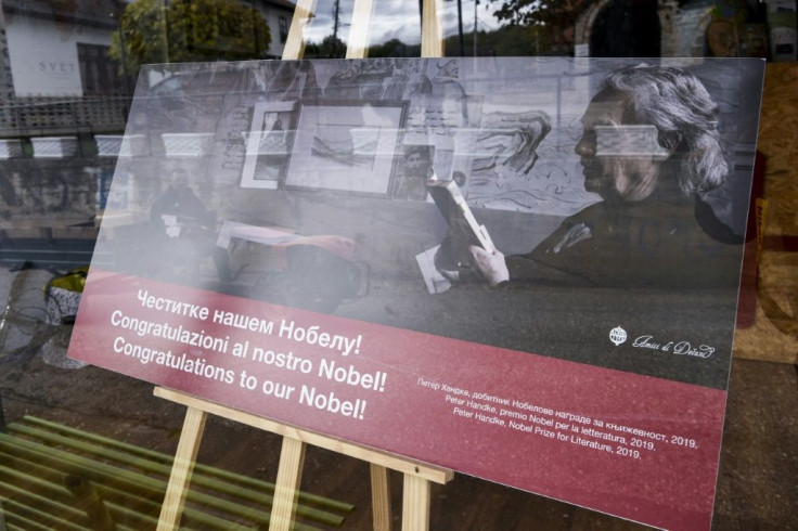 A farmer is reflected on a window of a shop featuring Nobel literature laureate Handke, who has made two large donations to the small wine-growing village of Velika Hoca and where everyone has one of his books