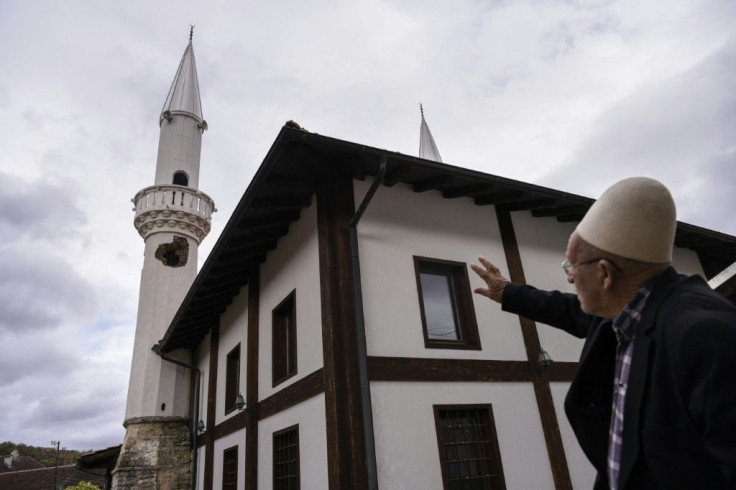 A Kosovo Albanian man points to a minaret destroyed during the war  in the neighbouring village of Hoce e Vogel -- a conflict which has left the communities divided, including on their view of Handke