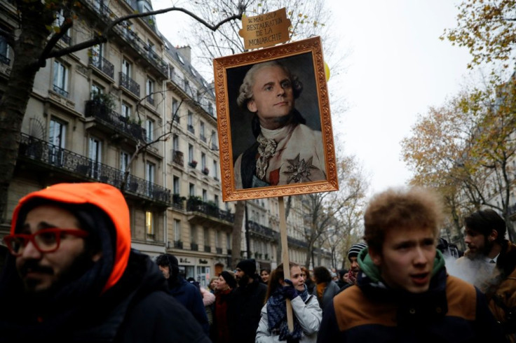 A Paris protester carries a portrait of  Emmanuel Macron depicted as royalty that says "May 14, 2017, restoration of the monarchy" -- a reference to his election date