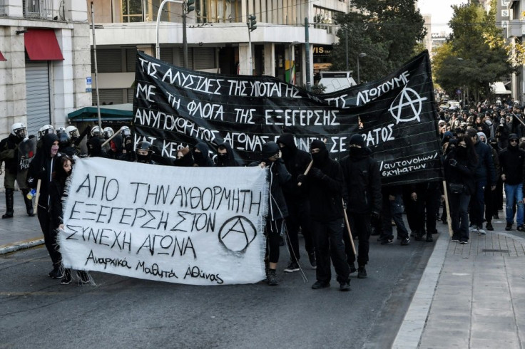 Black block protesters march behind a banner reading 'from a spontaneous uprising to the constant struggle' in Athens