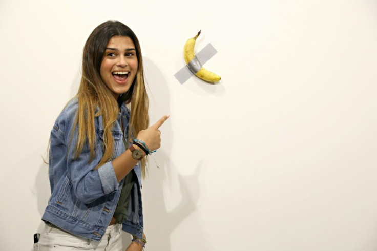 A woman poses with Maurizio Cattelan's "Comedian" at Art Basel Miami 2019 -- before a performance artist pulled it off the wall and ate it