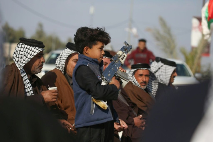 An Iraqi child carries a mock machine gun as armed members of Karbala clans take to the streets to declare their support for the Iraqi armed forces