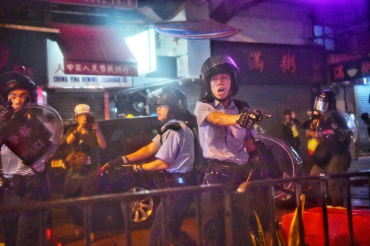 Police officers point their guns at protesters in Tseun Wan in Hong Kong in August