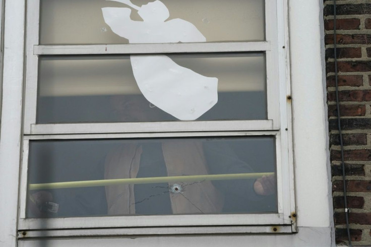 A construction worker looks over a bullet hole at the Sacred Heart School across the street from the Jewish deli targeted by shooters