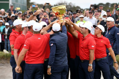 US team captain Tiger Woods (C, back to camera) and teammates celebrate with the trophy after winning the Presidents Cup golf tournament