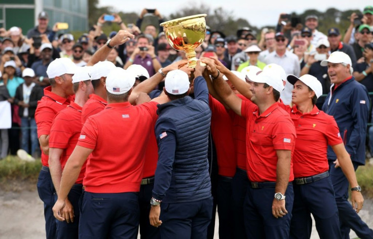 US team captain Tiger Woods (C, back to camera) and teammates celebrate with the trophy after winning the Presidents Cup golf tournament