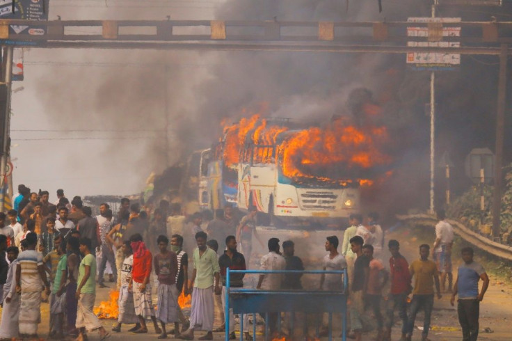 Protesters block a road after setting buses on fire during a demonstration against the Citizenship Amendment Bill in Howrah, on the outskirts of Kolkata