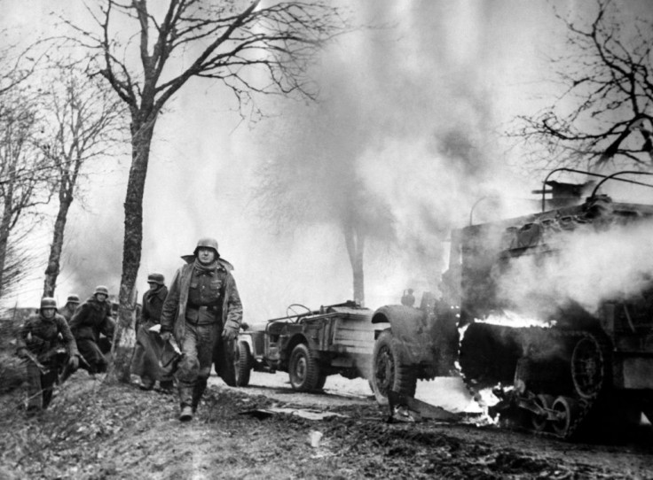 This photograph dated December 16, 1944, taken from a captured German's film,  shows German infantrymen passing burning US Army vehicles somewhere on the Western Front