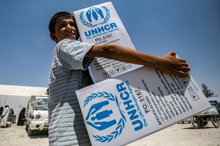A boy carries packages of UN humanitarian aid at al-Hol camp for displaced people in al-Hasakeh governorate, northeastern Syria, in July, 2019