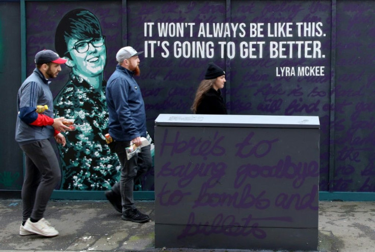 Belfast residents pass a mural featuring murdered journalist Lyra McKee, whose death sparked a new round of political talks chaired by the British and Irish Governments, in May 2019