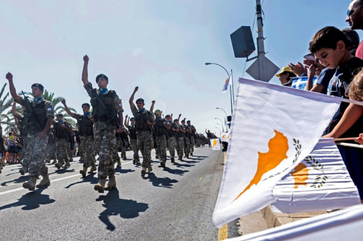People in Nicosia wave flags during a military parade marking the 59th anniversary of Cyprus' independence from British colonial rule in October 2019