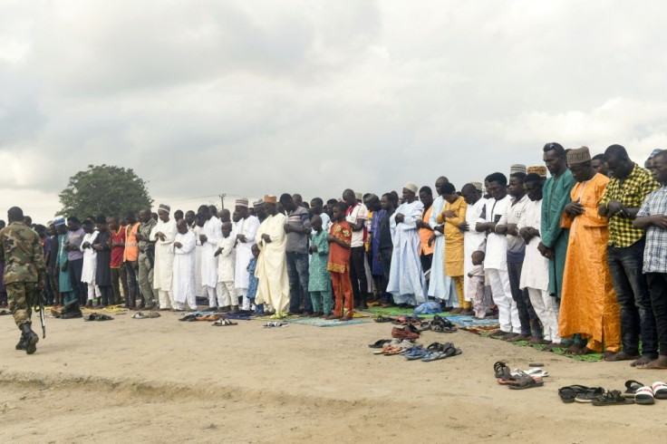 A soldier walk past Muslims as they pray near a gas station in Nigeria's Ogun State in August 2019