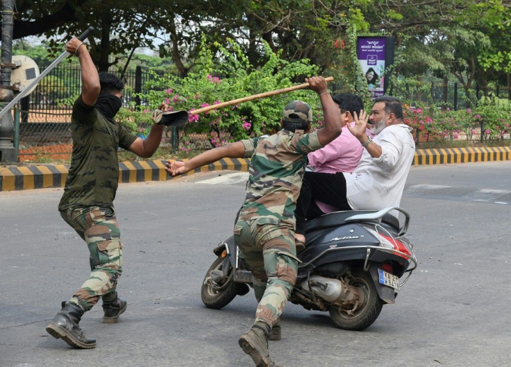 Karnataka Reserve Police Force members prepare to club two men who rode too close to a street barricade in Mangalore