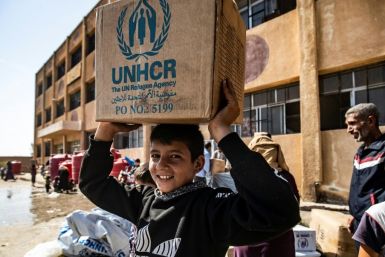 Displaced Syrians, who fled their homes in the border town of Ras al-Ain, receive humanitarian aid on October 12, 2019, in the town of Tal Tamr -- a UN resolution that would have extended aid for a year has been vetoed