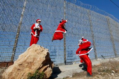 Palestinian children wearing Santa Claus costumes play near Israel's separation barrier west of Bethlehem in the occupied West Bank