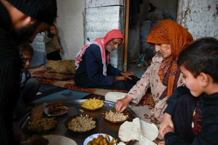 Umm Khaled and her family share a meal in their home in Haarem, dipping flat bread into dishes she prepared using mushrooms instead of meat