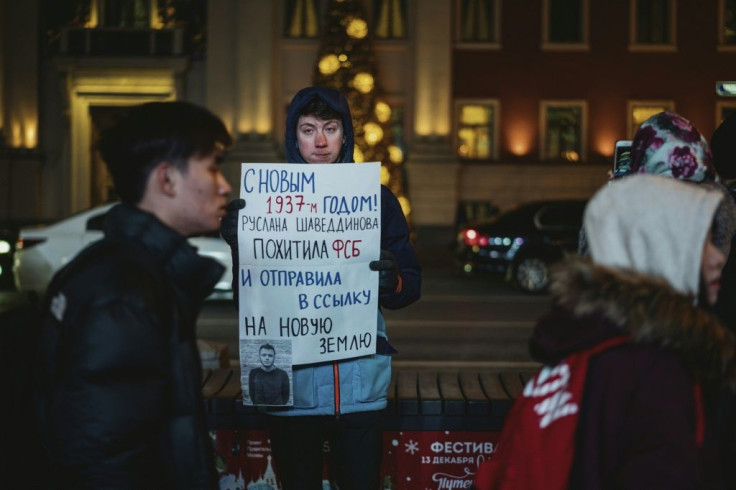 A man holds a poster reading "Happy New Year 1937, Ruslan Shaveddinov has been kidnapped by the FSB (security service) and exiled to Novaya Zemlya" during a protest in central Moscow