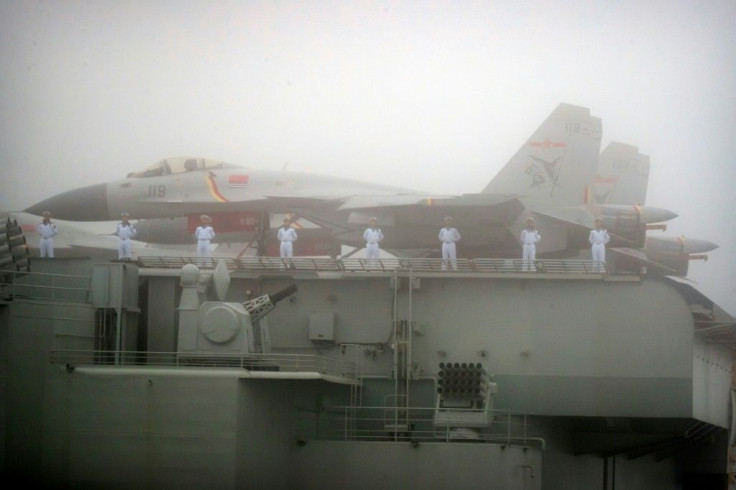 Sailors stand near fighter jets on the deck of the Chinese People's Liberation Army Navy aircraft carrier Liaoning