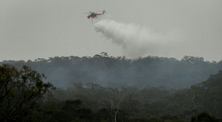A helicopter dumps water on a bushfire in the outer suburbs of Melbourne