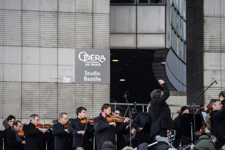 Paris Opera musicians set up on sunlit steps outside the Bastille Opera to play for several hundred passers-by
