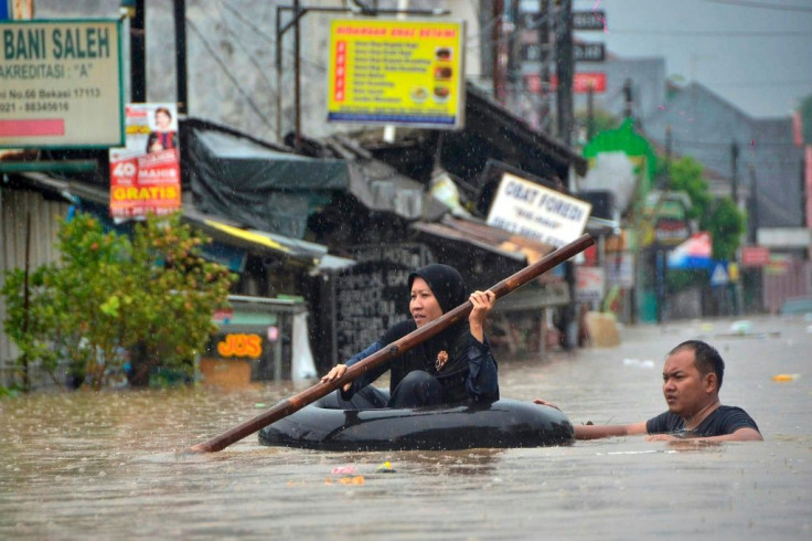 A woman paddles through flood waters on an inner tube in Bekasi, near Jakarta