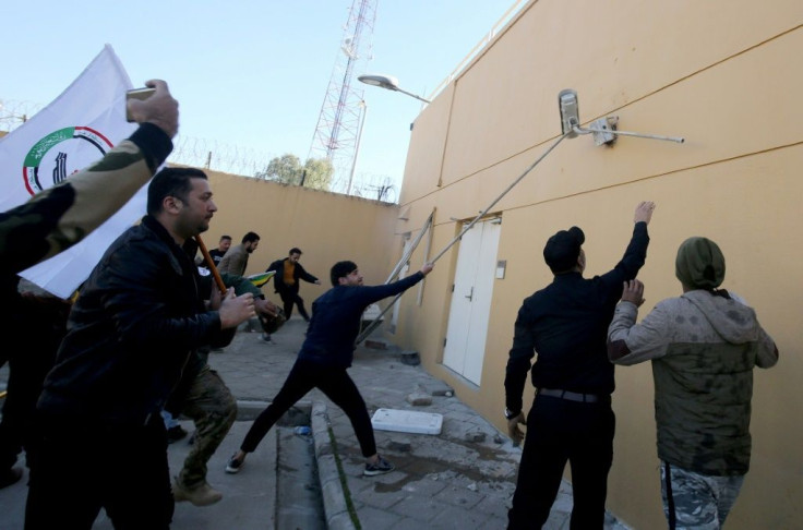 Iraqi protesters tear a security camera off a wall at the US embassy compound in Baghdad