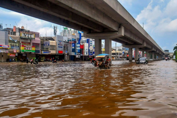 A horse pulls a carriage through a flooded road in Jakarta