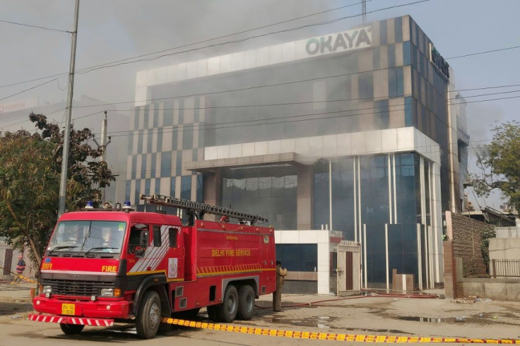 A Delhi fire truck is parked next to the site of a fire and building collapse