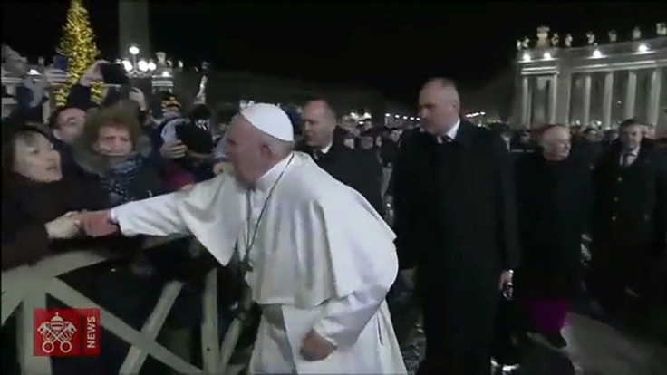 A frame grab taken from a handout video made available by Vatican Media on January 1, 2020 shows a lady (L) grabbing at Pope Francis's hands as he greets Catholic faithful as he arrives to celebrate New Year's Eve mass in Vatican City