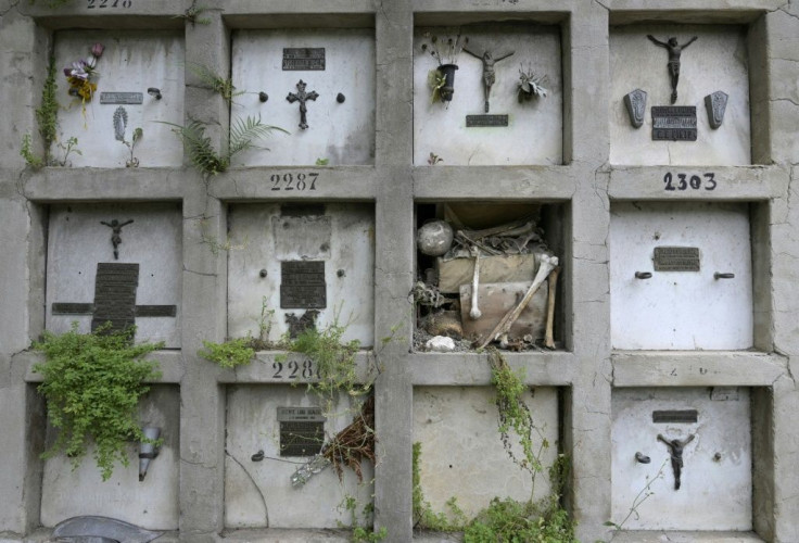 Human remains are visible inside damaged niches that are overgrown with vegetation at the Chacarita Cemetery in Buenos Aires, Argentina