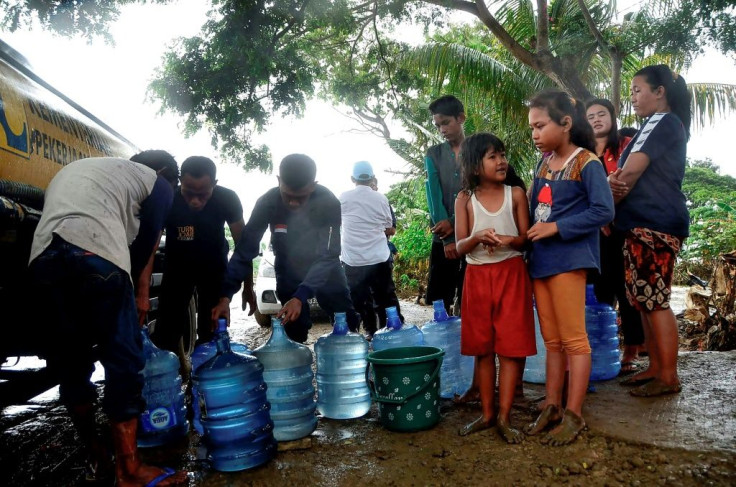 People wait to get fresh water from a truck in their flood affected village in Bekasi, West Java
