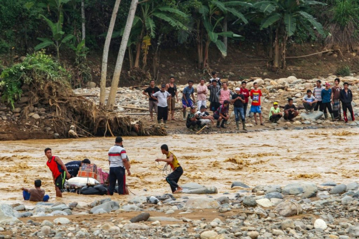 Indonesian villagers use inner tubes to deliver supplies across a river at Banjar Irigasi in Lebak, Banten province