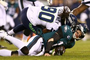 Philadelphia Eagles quarterback Carson Wentz, bottom, is hit by Seattle's Jadeveon Clowney and sent off for the rest of Sunday's NFL playoff game
