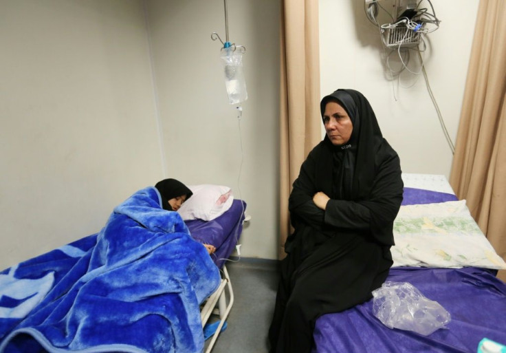 An Iranian woman sits next to a relative injured in the stampede