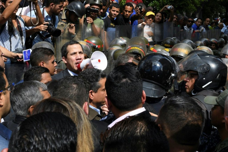 Venezuelan opposition leader and self-proclaimed acting president Juan Guaido speaks on a loudspeaker as helmeted security forces try to block his entry to the National Assembly