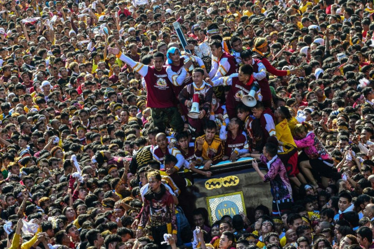 Devotees clamber up the metal float carrying the life-size statue in an attempt to touch the icon