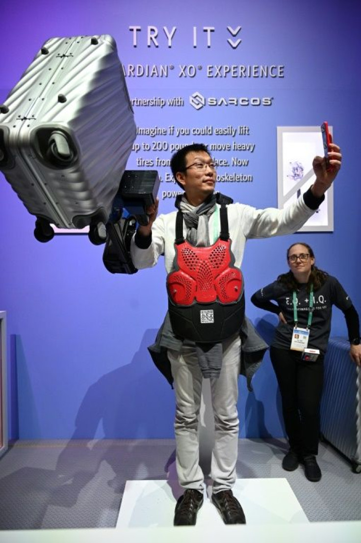 An attendee takes a selfie as he lifts a 22.7 kg suitcase with the help of the Sarcos Guardian XO exoskeleton arm at the 2020 Consumer Electronics Show